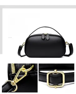 Detail of black pebbled leather round handbag featuring gold double zippers and strap