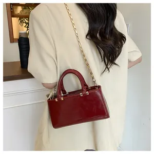 Model view of burgundy patent leather square bag with gold chain and top handle