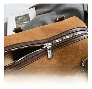 Detail of silver metal zipper and brown suede texture on a vintage cylinder bag