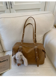 Dettaglio della borsa tote in pelle marrone con occhielli argentati e ciondolo a coniglio