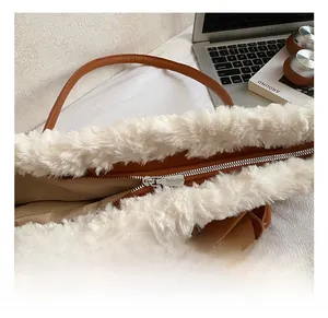 Close-up of premium silver metal zipper and faux fur trim on a brown suede handbag