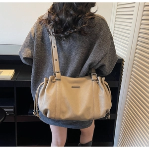 Detail of khaki pebbled leather tote with drawstring design and adjustable straps
