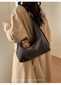 Detail of dark grey hobo bag with matte texture and cute plush bear accessory