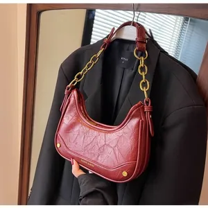 Detail of burgundy crescent bag with vintage pleated leather and gold chain strap