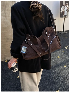 Detail view of brown suede tote bag with silver ring accent and side zipper pocket