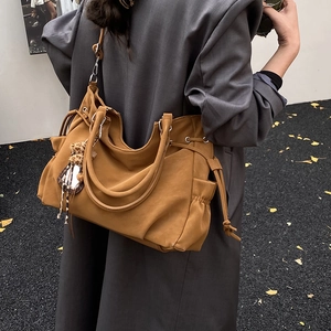 Brown faux leather tote bag with side drawstrings worn by model in autumn scenery