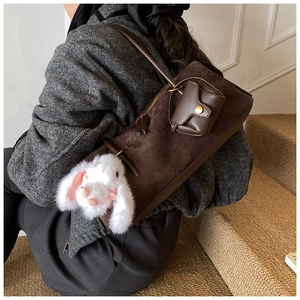 Detail der dunkelbraunen Wildleder-Schultertasche mit weißem Plüschhasen und kleiner Tasche