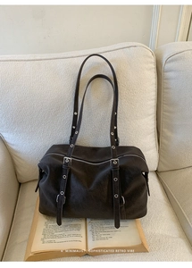 Dettaglio della borsa tote vintage marrone scuro con occhielli argentati sui due spallacci