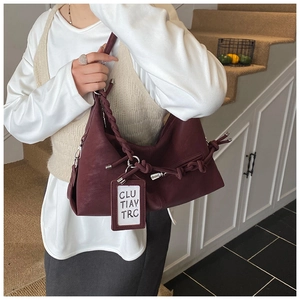 Detail of burgundy leather hobo bag featuring woven strap and designer knot detail