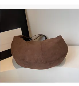 Dettaglio della borsa a mezzaluna in camoscio marrone scuro con tracolla in pelle
