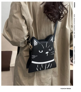 Détail du sac bandoulière chat noir avec broderies et boucles dorées porté par un modèle