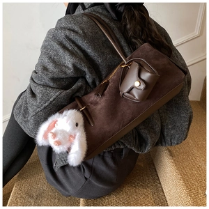 Details einer dunkelbraunen Wildleder-Schultertasche mit Plüschhasen-Anhänger