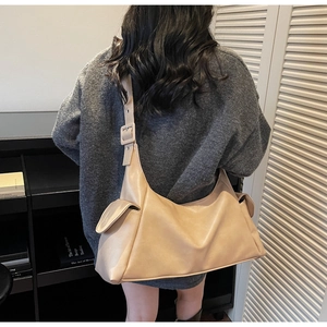 Detail of beige faux leather tote with wide shoulder strap and functional side flap pockets