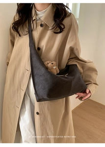 Detailed macro view of soft matte dark leather texture and cute plush bear charm on tote bag