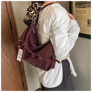 Detail of burgundy leather tote with braided strap, knot tassels and leopard scrunchie