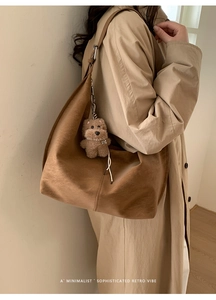 Detail of a brown suede shoulder bag featuring a cute plush bear charm on the strap