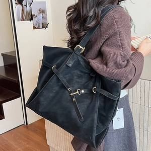 Large black faux leather tote bag with gold buckles worn by model for daily casual style