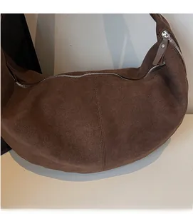 Dettaglio della trama in pelle scamosciata marrone scuro e zip in metallo della borsa