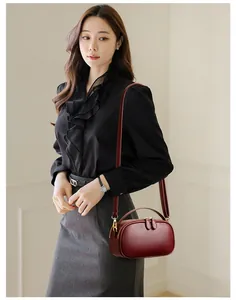 Detail of burgundy leather mini bag with gold hardware and dual zipper closure on a model