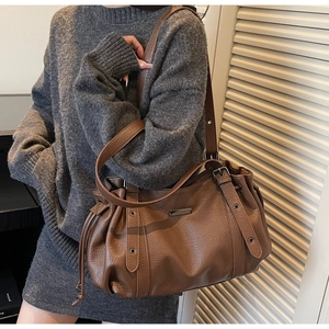 Detail of vintage brown lychee grain leather handbag featuring drawstring pleats and metal trim