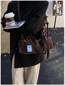 Close-up of deep brown suede tote bag with side pockets and cute bear charm in street setting