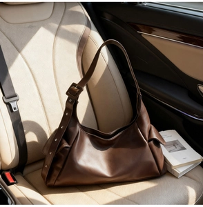 Detail of dark brown leather hobo bag with adjustable strap on a luxury car seat