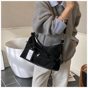 Détail du sac hobo noir à texture mate et bandoulière nouée élégante pour un look chic
