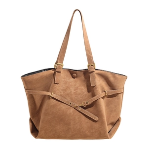Large brown faux leather tote bag with cross straps and gold hardware on white background