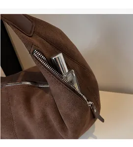 Dettaglio della tasca laterale con zip su borsa a tracolla marrone opaca e spazio