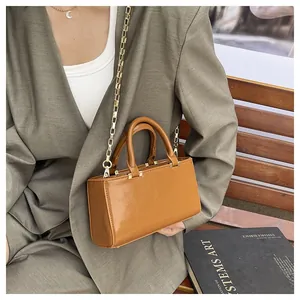 Detail of caramel brown glossy leather tote bag with gold hardware on wooden bench