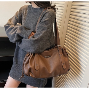 Detail of vintage brown pebble grain leather tote bag with drawstring sides and metal logo