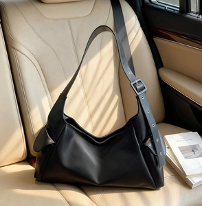 Detail of black leather hobo bag with adjustable buckle strap and side flap pocket