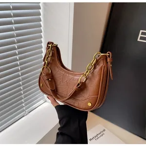 Detail of caramel brown crescent bag with wrinkled leather texture and gold chain link