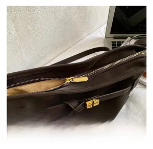 Close-up of golden metal zipper and buckle detail on vintage brown leather tote bag
