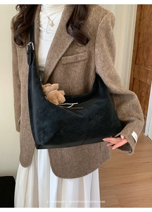 Detail of black semi-moon leather crossbody bag with cute brown teddy bear charm