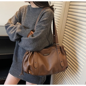 Detail of lychee pattern brown tote bag featuring drawstring design and silver metal label