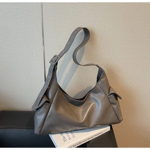 Close-up of matte leather tote bag detail with adjustable strap and large square buckle