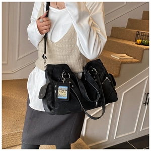 Detail of black matte tote bag with utility pockets and a cute cartoon bear accessory