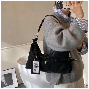 Detail of black suede shoulder bag featuring braided rope strap and decorative zipper