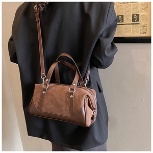 Brown vintage Boston bag with adjustable strap worn by a model against a retro wall