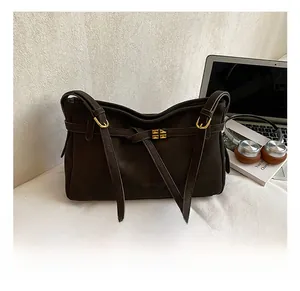 Detail of dark brown suede shoulder bag with golden square buckle in a lifestyle setting