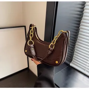 Detailed close-up of dark brown crescent bag with gold chain strap and leather texture