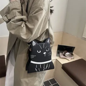 Détail du sac bandoulière en forme de chat avec broderie blanche sur cuir synthétique noir