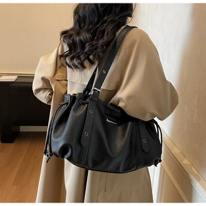 Detail of black pebbled leather tote bag with drawstring closure and silver eyelets