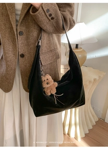 Detail view of black matte hobo bag with a cute brown plush bear charm accessory