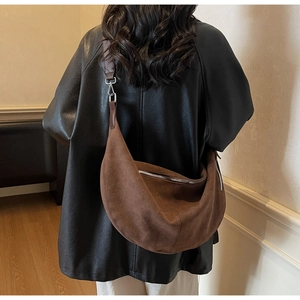 Detail of dark brown suede crescent bag featuring silver zipper and adjustable strap