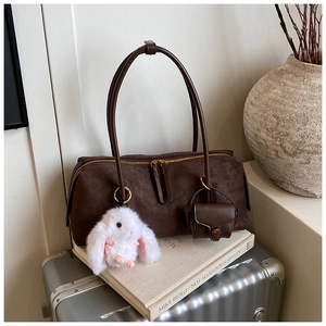 Details einer braunen Boston-Tasche aus Wildleder mit langem Griff und Hasenanhänger
