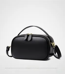 Detail view of black pebble leather texture and gold metal hardware on handbag