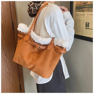 Détail d'un sac cabas en daim marron avec garniture en fausse fourrure blanche et boucles