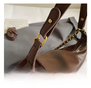 Detail of gold metal hardware and chain strap on a brown plaid vintage underarm bag